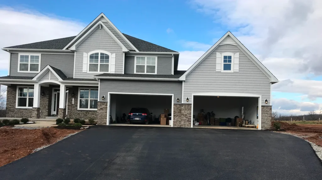 A two story grey house with dark roof shingles and stone accents
